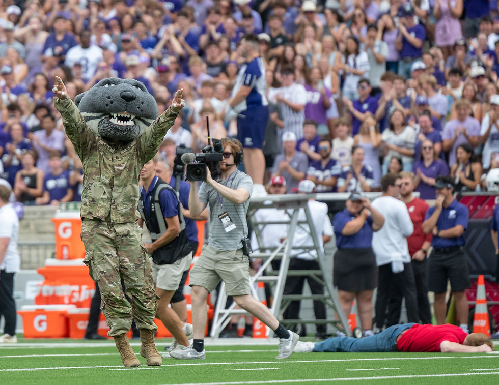 Willie the Wildcat points into the air with both hands after tackling the opposing team's fake mascot.