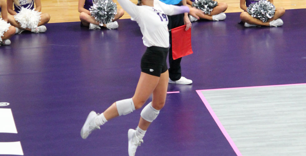 A K-State Volleyball player jumps in the air and prepares to spike a ball.