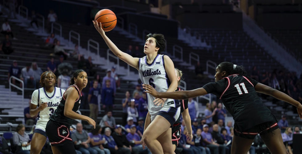 A K-State basketball player drives into the lane for a layup.
