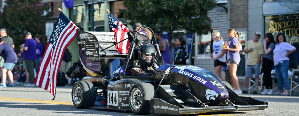 A car from the F1 Racing club has american flags hanging off the side of it.