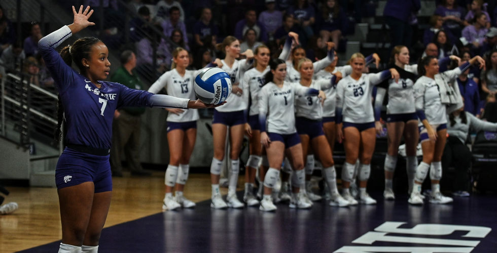 A K-State volleyball player prepares to hit the ball over the net.