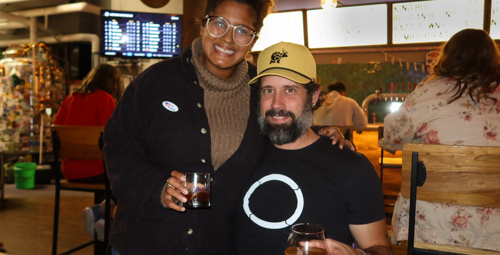 Two individuals smiling with drinks at Manhattan Brewing Company.