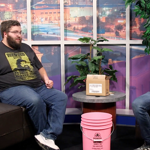 Peter and Jacob sit on chairs with a box and pink bucket between them.