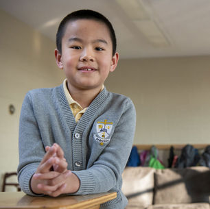 A child in a school uniform with hands folded