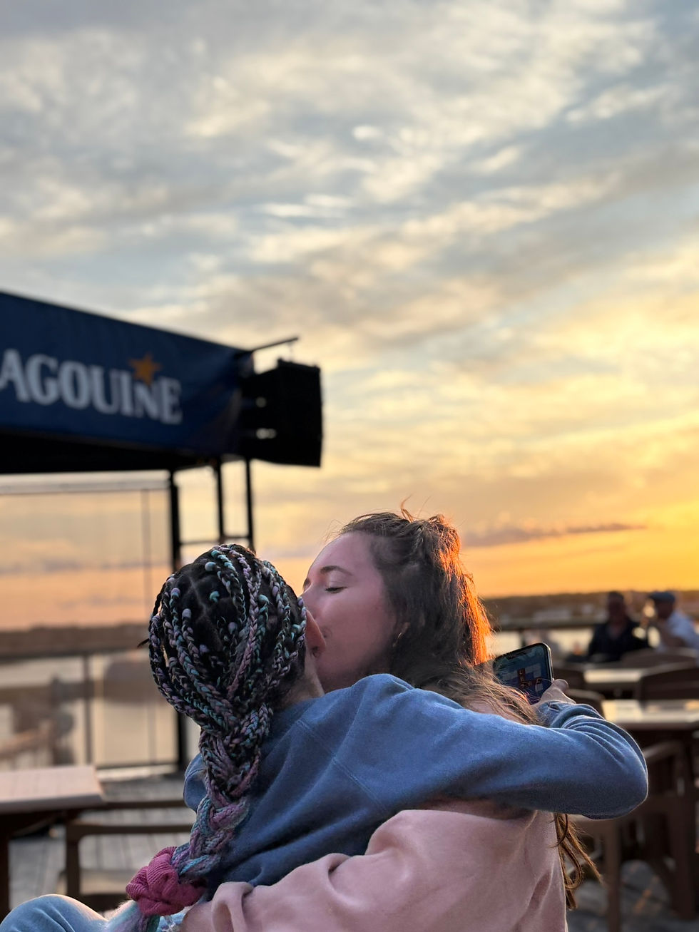 Maman qui donne un bisou à sa fille dans ses bras avec un coucher de soleil