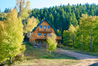 Gunnison area log home surrounded by fall trees.