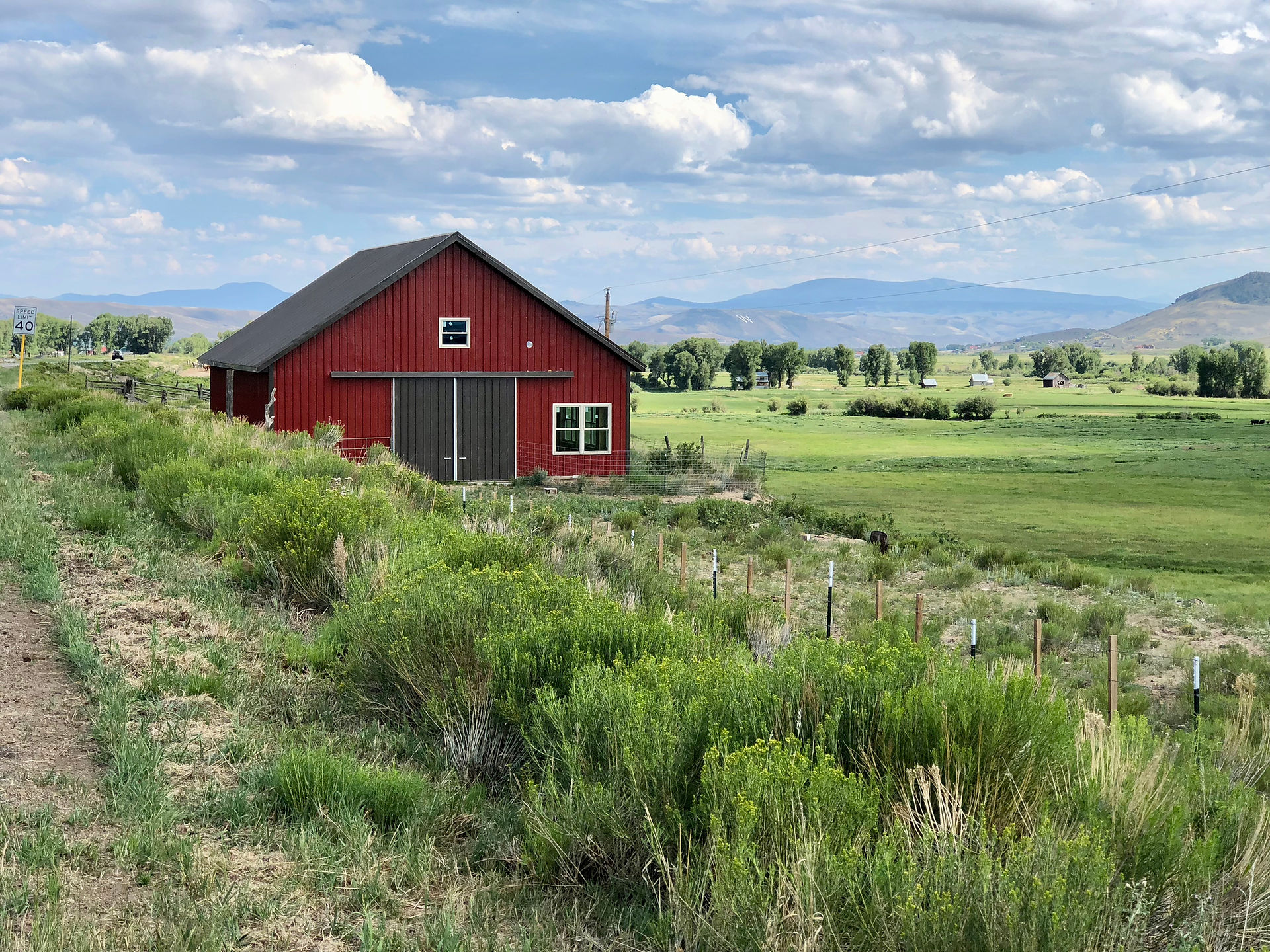 West Red Mountain Ranch - red bard with mountains in background.