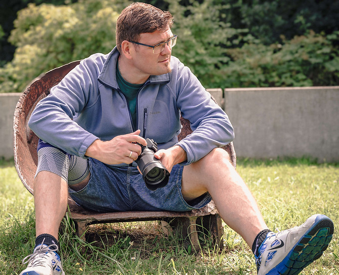 Mann mit Brille sitzt und hält Kamera, in Jena, Bastiontour-Fotoshoot.
