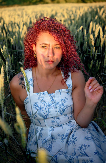 Rotschopfige Frau posiert im Feld, Blumenkleid, Portraitfotografie, Bastiontour-Fotoshoot.