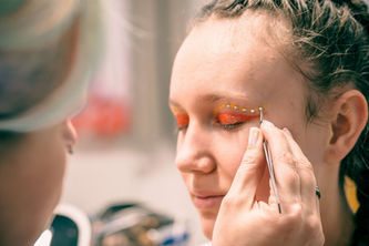 Frau beim Schminken, orangefarbenes Make-up, Person mit Pinzette, Nahaufnahme, Bastiontour-Fotoshoot