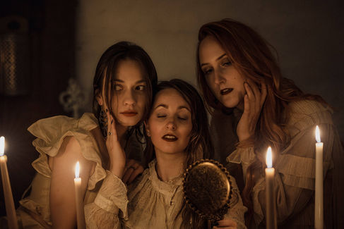 Three women with candles looking into a mirror. Portraitfotografie Jena – Bastiontour-Fotoshoot