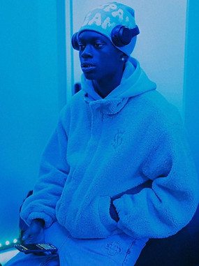Image of LeoStayTrill for the song Pink Lemonade. He's wearing beanie and headphones over the top looking off to the left. the image have a blue overlay. 