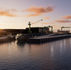 Rendering of Saronic’s planned Port Alpha shipyard showing waterfront gantry cranes, vessels, and production facilities at sunset.