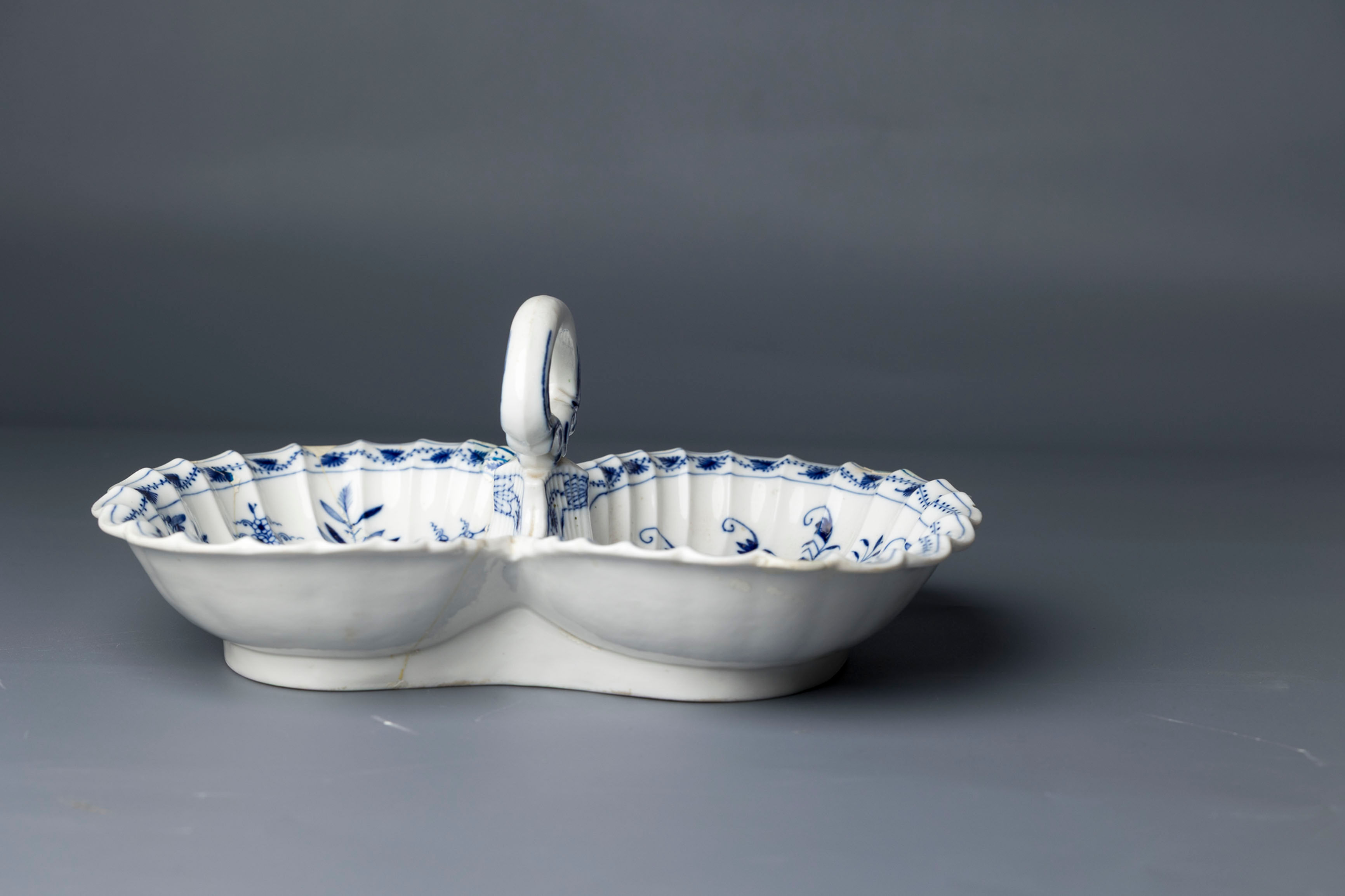 This is an ornate twin-shell porcelain dish joined at the base with sculpted central ring handle.