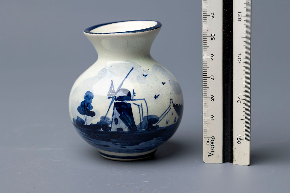 This is a small bulbous vase featuring a hand-painted traditional Dutch windmill scene, rendered in classic cobalt blue under