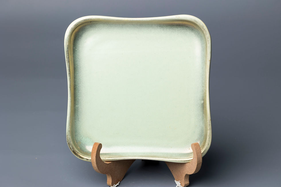 his is a mid-century modern West German ceramic plate in a soft, satin-matte celadon or sage-green glaze