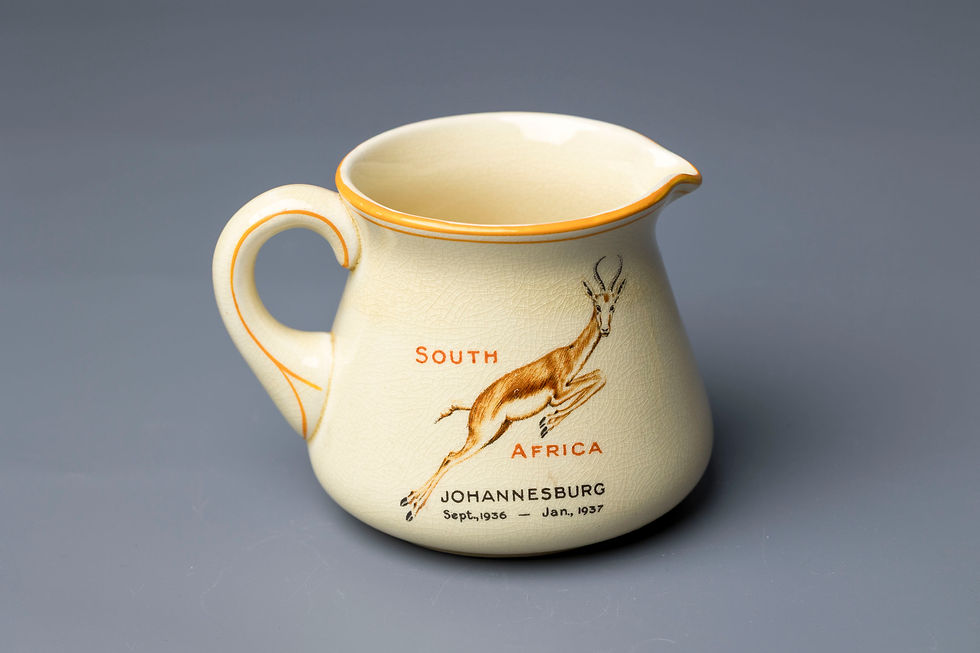 This is a cream-colored earthenware commemorative jug produced by Crown Devon (Fieldings) for the Empire Exhibition