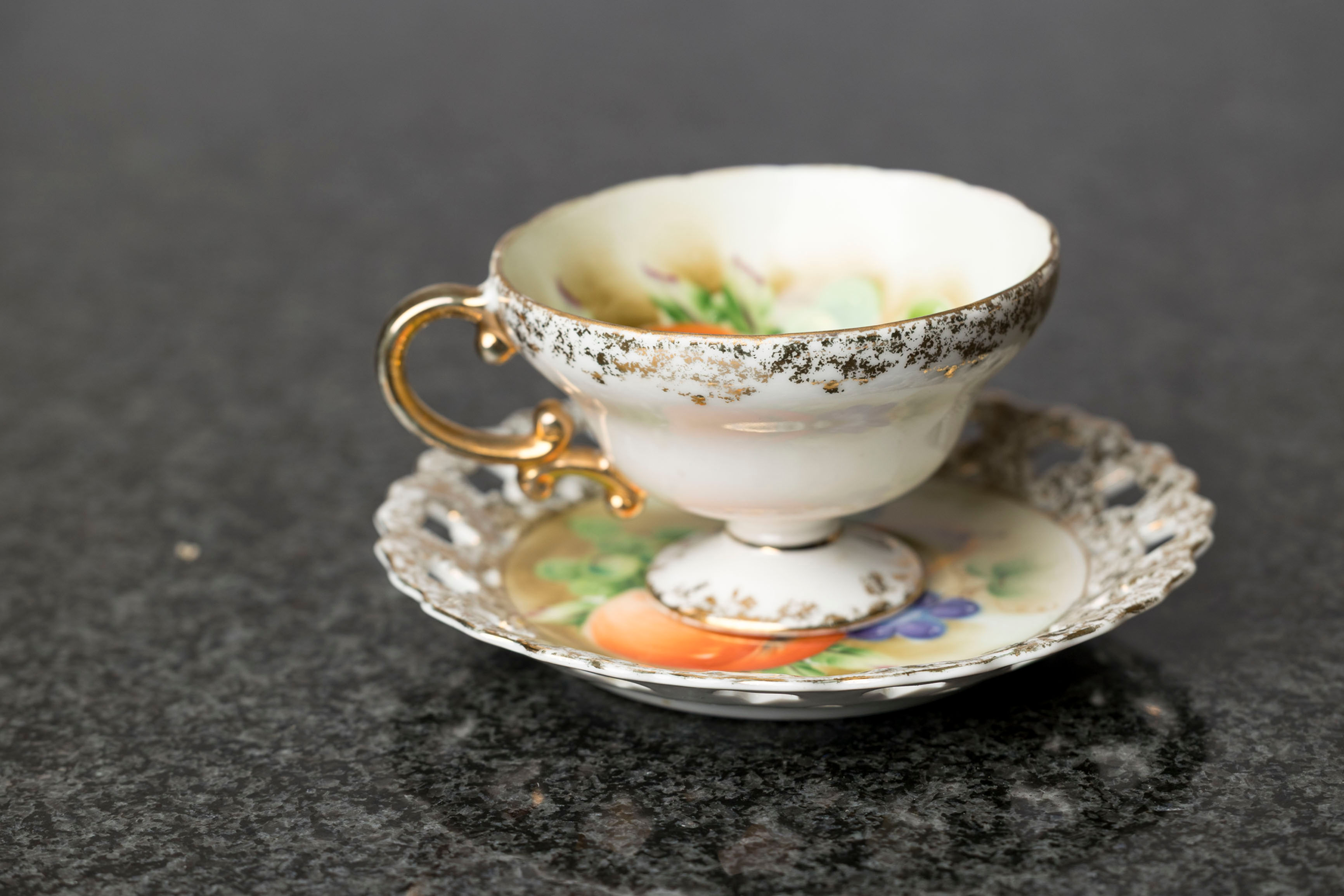 The pierced saucer and gold accents are features seen in Viennese, Czechoslovakian, Austrian or German porcelain rather than