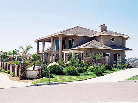 Large stucco house with pillars and a landscaped yard