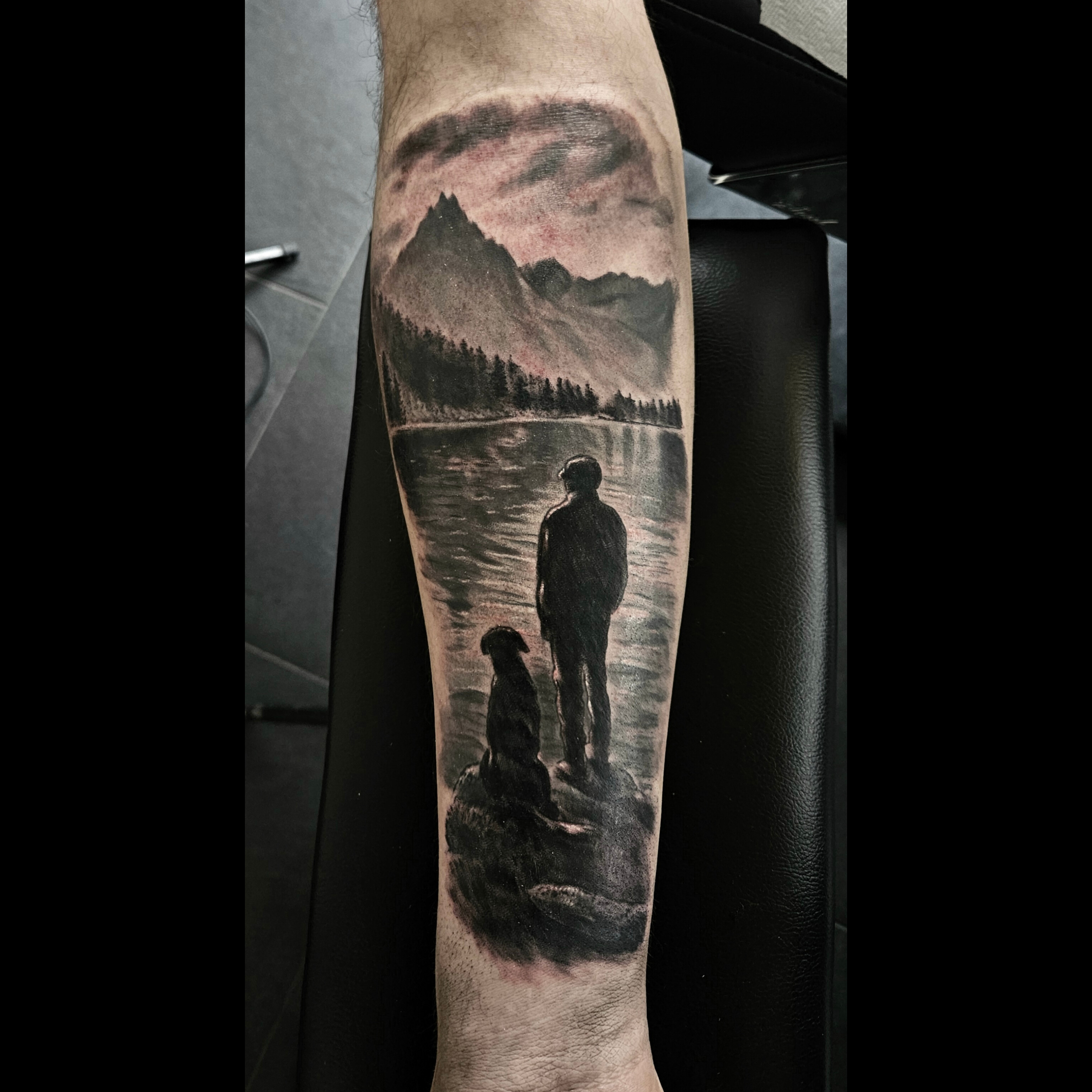 Black and grey mountain memorial tattoo with a man and dog