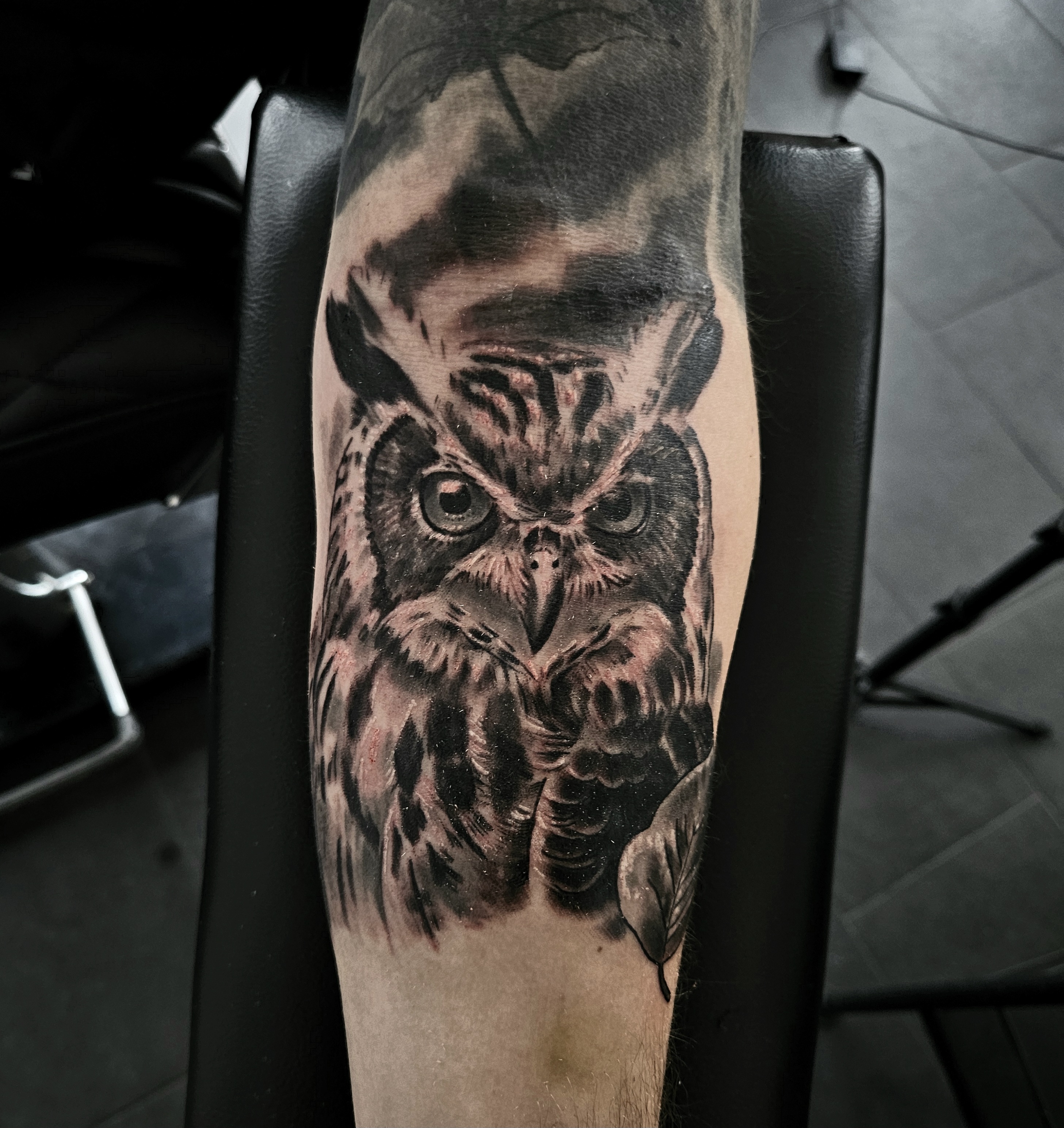 Detailed black and grey owl forearm tattoo