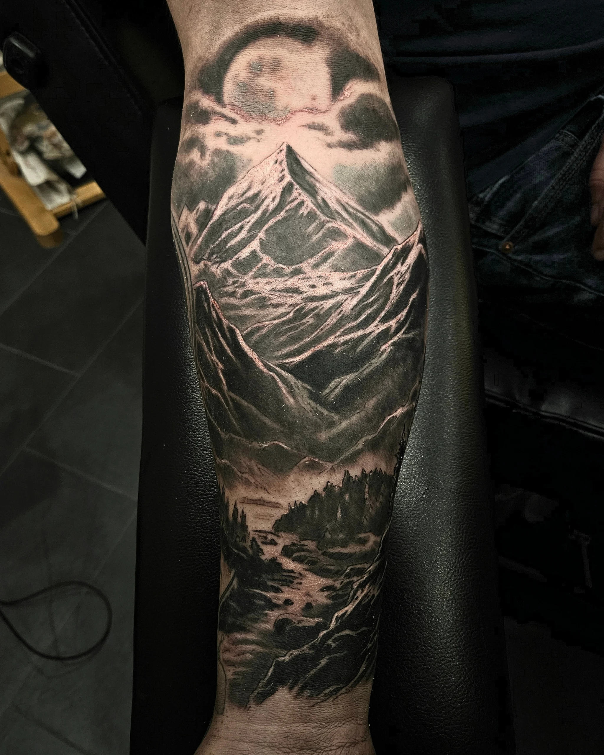 Black and grey mountain landscape tattoo on a forearm