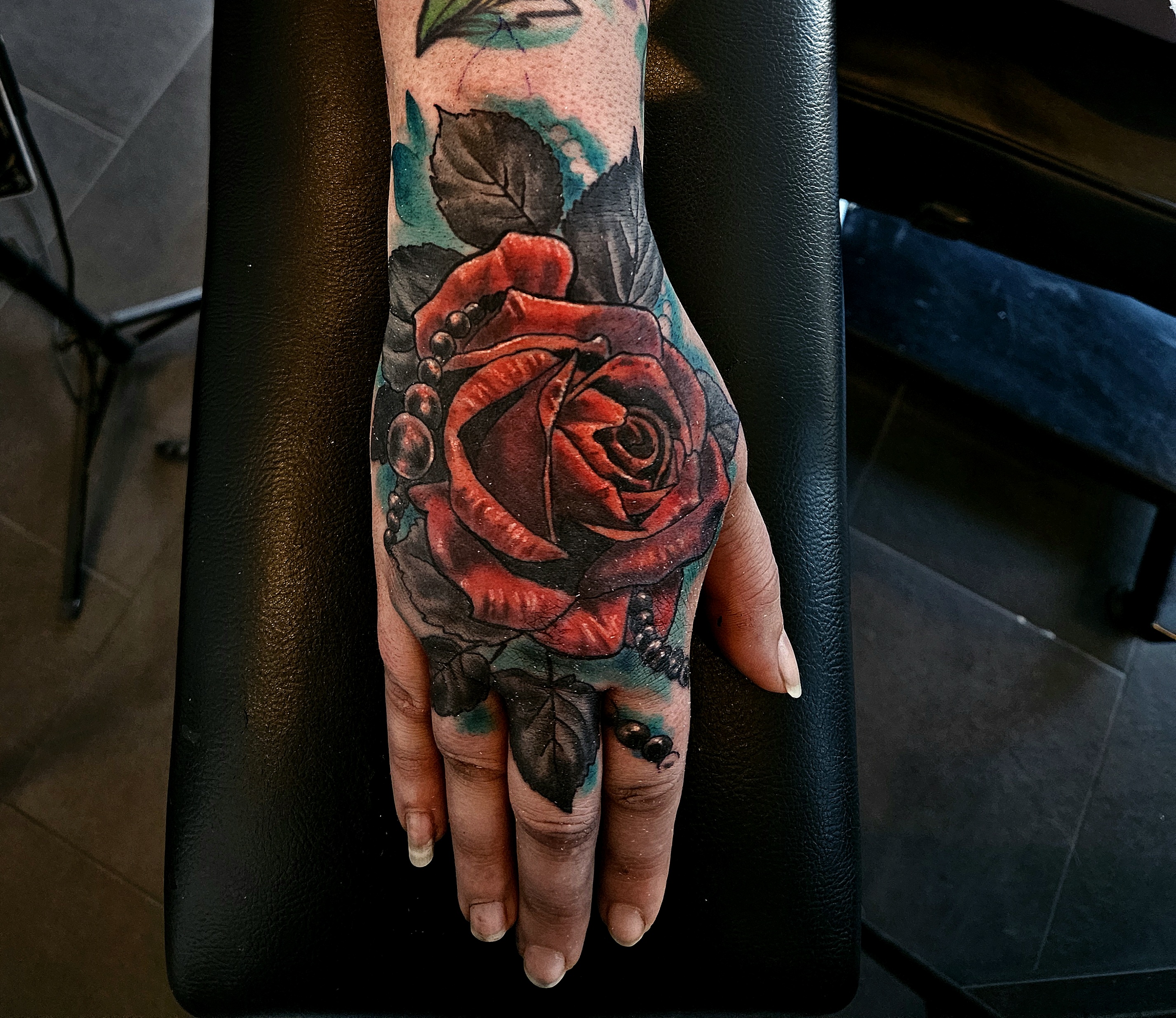 Red rose tattoo across the hand