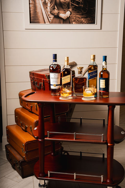 Various whiskey bottles and glasses on a wooden bar cart, Flagler Station.