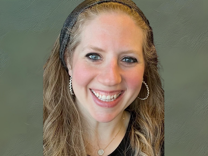 Smiling woman with headband, hoop earrings, and green backdrop.