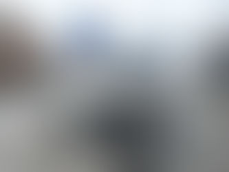 Vintage motorcycle parked at snowy Oberalppass, 2046 m, beside wooden buildings. Sign reads "Kil. 46.16 von Altdorf." Cloudy sky.