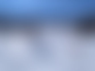 Skiers glide down a snowy slope in Sestriere, Italy under a bright blue sky, surrounded by trees. A ski lift carries people uphill on a sunny day.