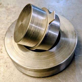 Metal press tools stacked on shiny metal surface with visible grooved patterns, creating an industrial feel.