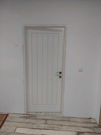 A white, panelled door with vertical lines and a brass handle