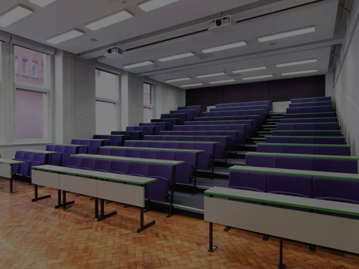 Modern lecture hall with purple seats, white desks, and wooden floor