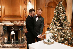 Gay couple cutting elegant single tier wedding cake with fresh florals in Yorkshire