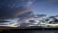 Stormy night sky over the sea with pale yellow on the horizon