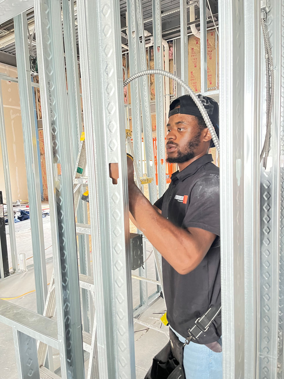 K Engineering electrician running new wiring through metal-stud framing