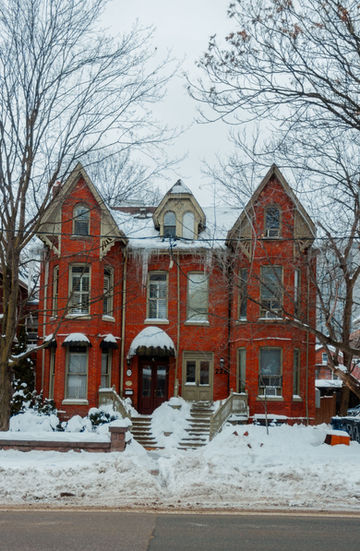 Red brick Victorian house covered in snow and icicles