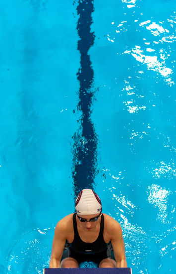 Swimmer in cap and goggles in a blue pool lane