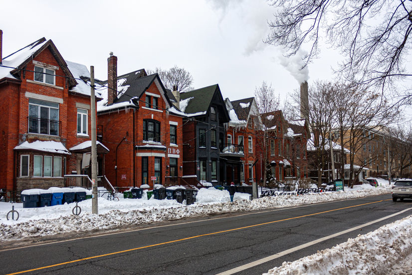 Row of brick houses covered in snow, with a smoking chimney.