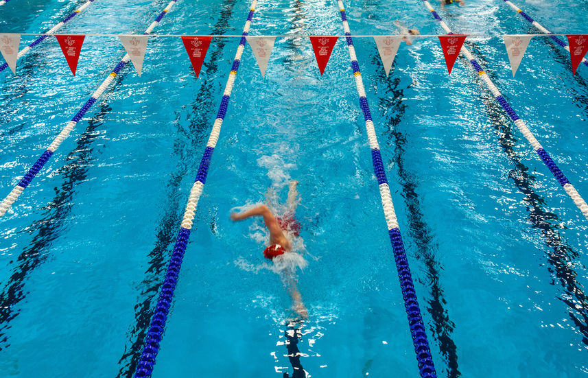 Swimmer doing backstroke in a lane with flags