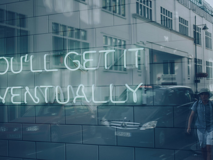 Neon sign in a window reading You'll get it eventually