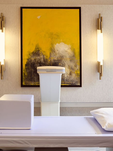 Modern therapy room with massage table and yellow art.