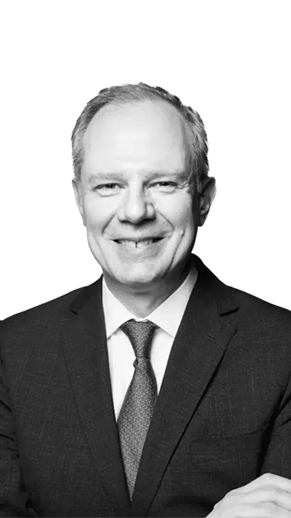 Portrait of Dr Charlie Cox, Cardiothoracic Intensive Care Consultant and Endurance Athlete at Reborne Longevity - a Harley Street clinic, specialising in longevity medicine. The image is in black and white, emphasising the Harley Street doctor's professionalism and patient-first approach. He has dark hair, is smiling and is wearing a shirt.