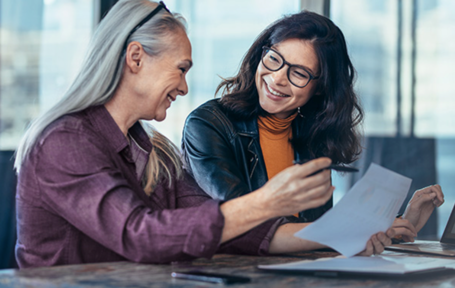 Two business women smile together during a business meeting