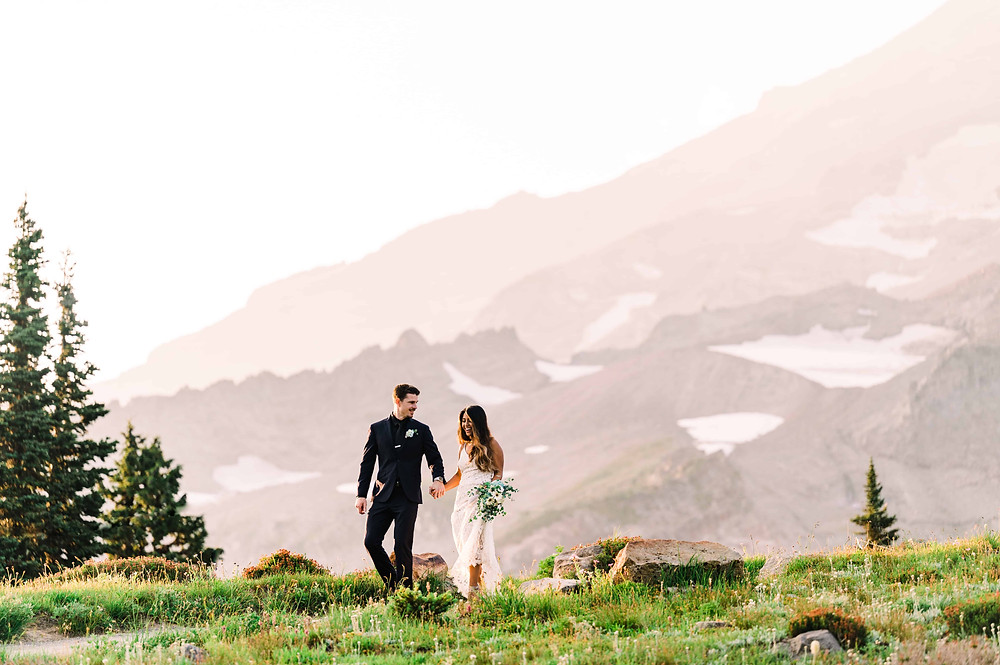 A couple holds hands and laughs on their wedding day at Mt Rainier National Park
