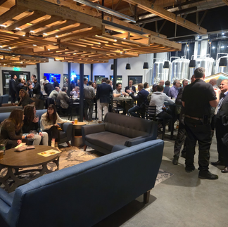 A group of people mingling at a party in a brewery