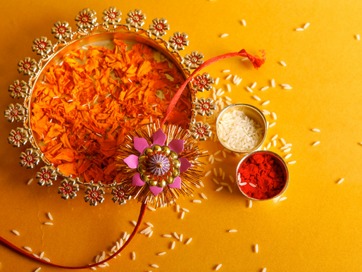 a rakhi on a decorative plate filled with flower and vermilin ,rice gain are in two small bowl