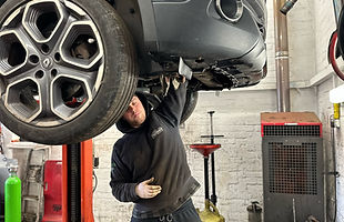 mechanic working on hoisted vehicle