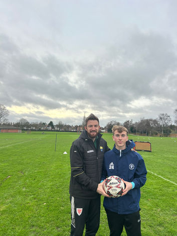 Football coach and male student holding football